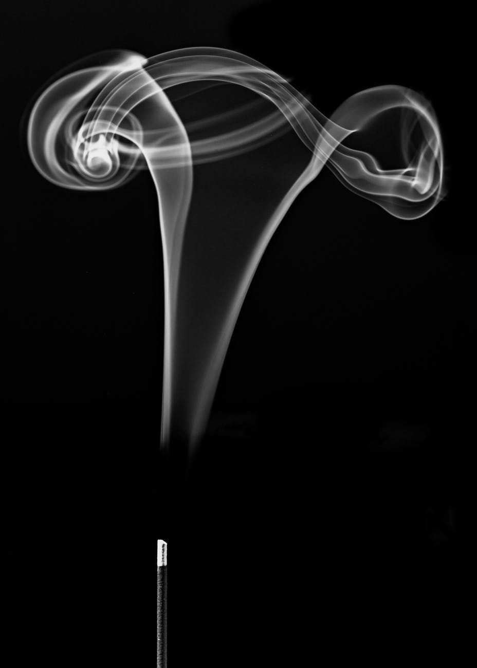 scent fume of burning incense stick against black background