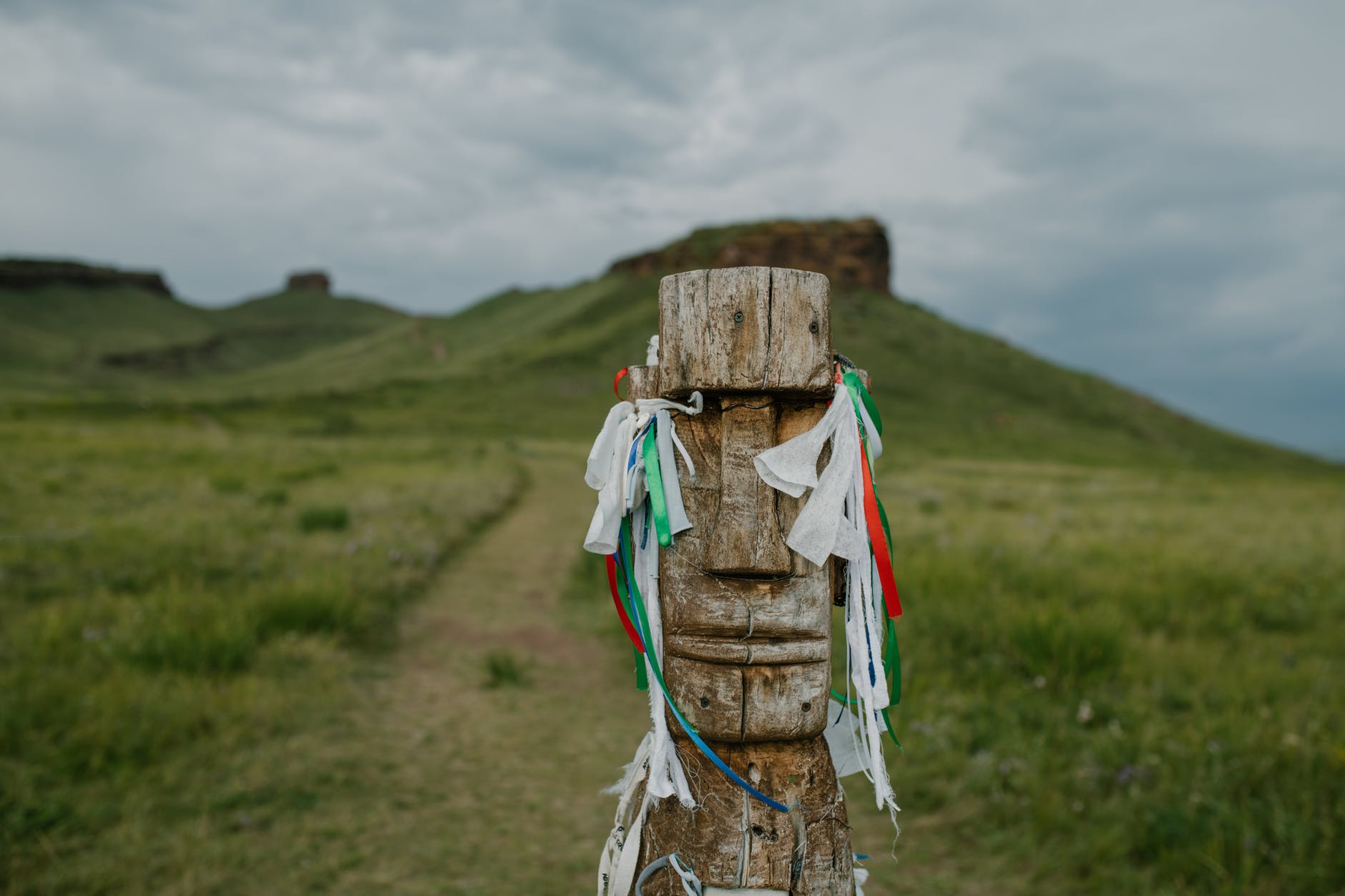 wooden idol with wish ribbons on grassy path