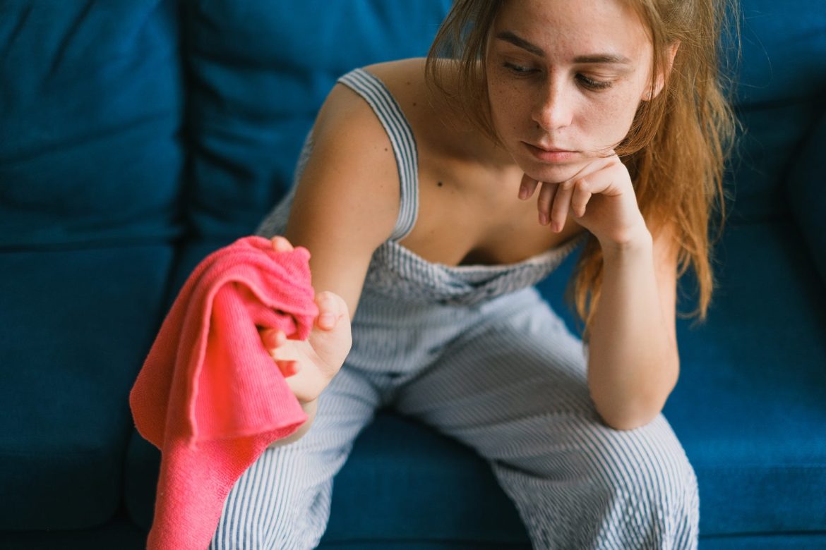 tired young woman resting on sofa after household chores at home