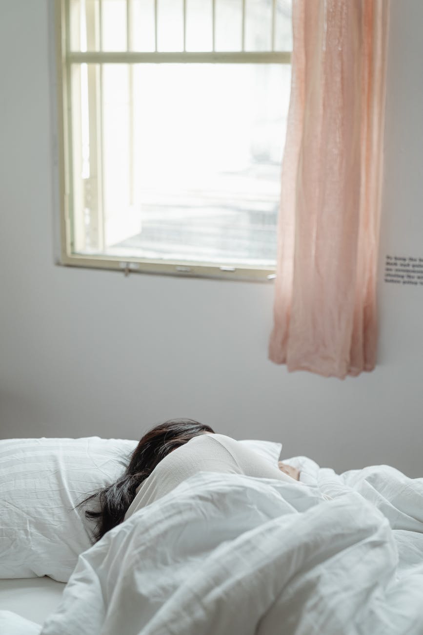 woman lying on bed near window