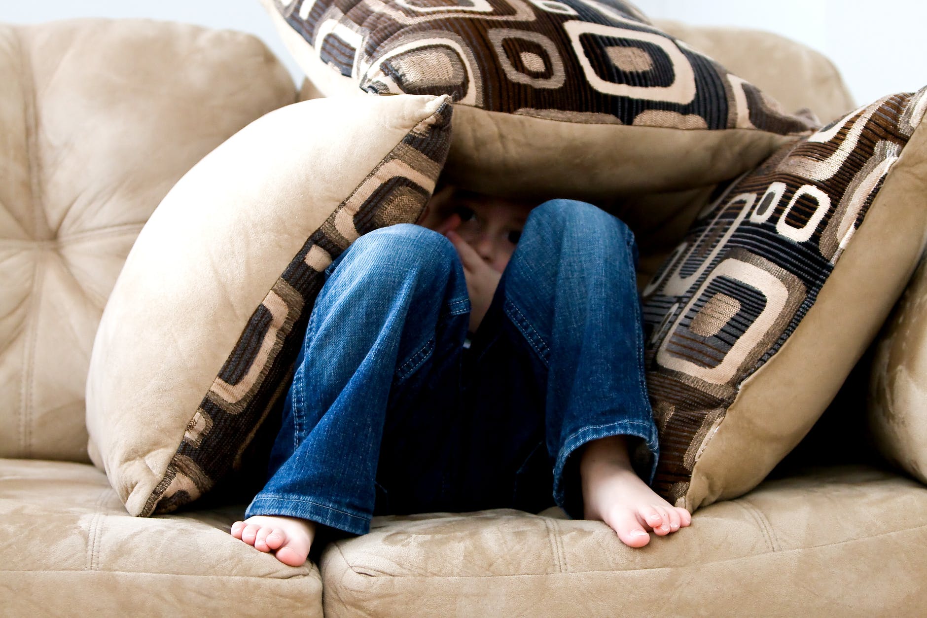 kid hiding on pillows