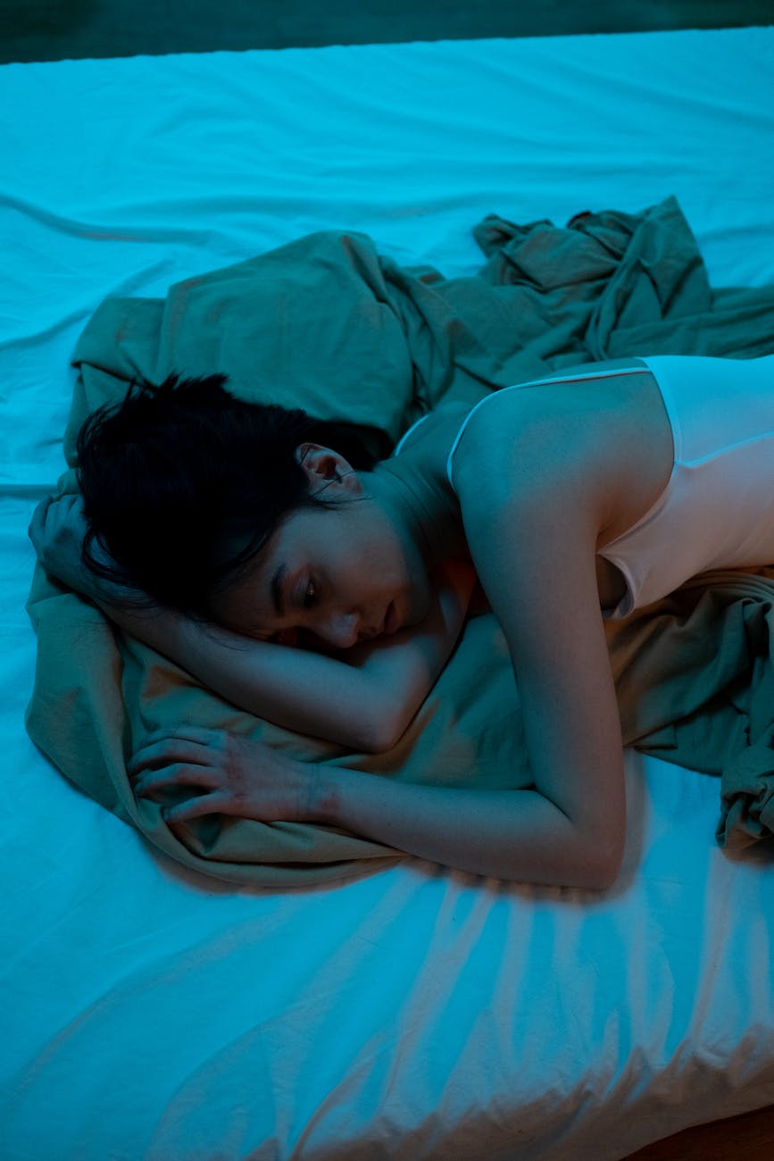 a woman in white tank top lying on bed