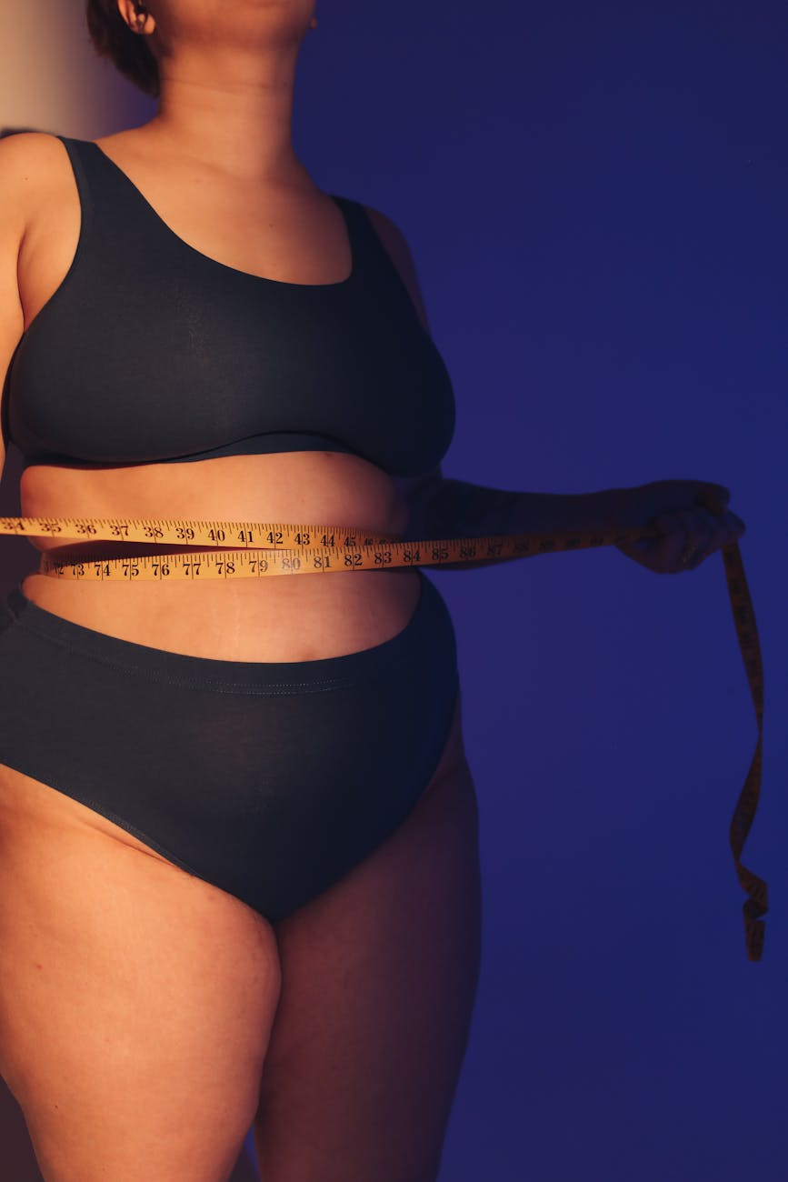 a woman in black tank top holding a tape measure